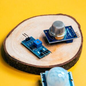 A photo of modern robotics sensors displayed on a wooden slice against a vibrant yellow background.