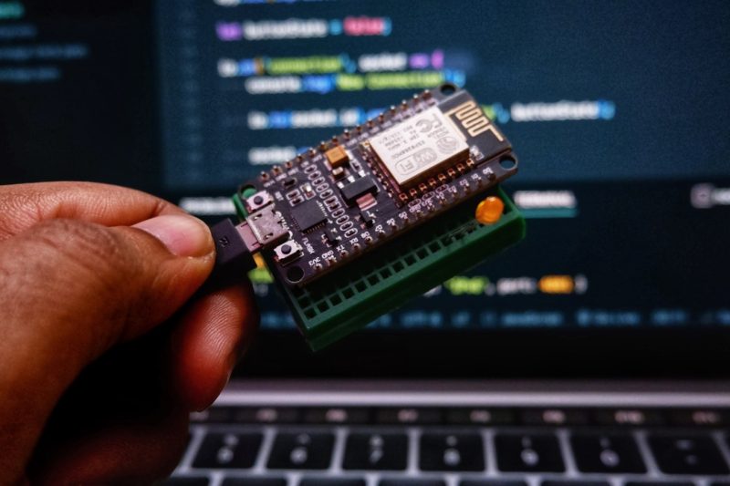 a person holding a small device in front of a laptop